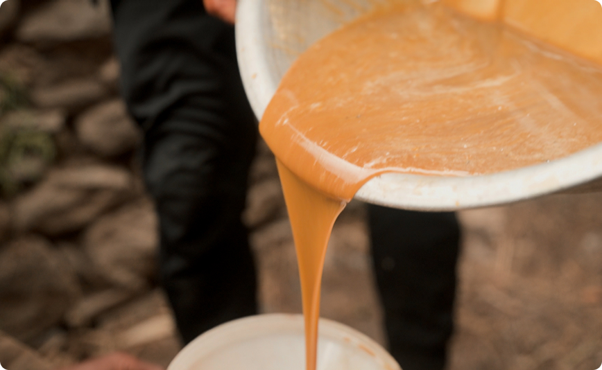 Raw mad honey being poured from a bowl in the field in Nepal