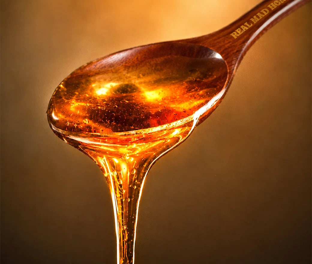 Raw mad honey running off a wooden spoon