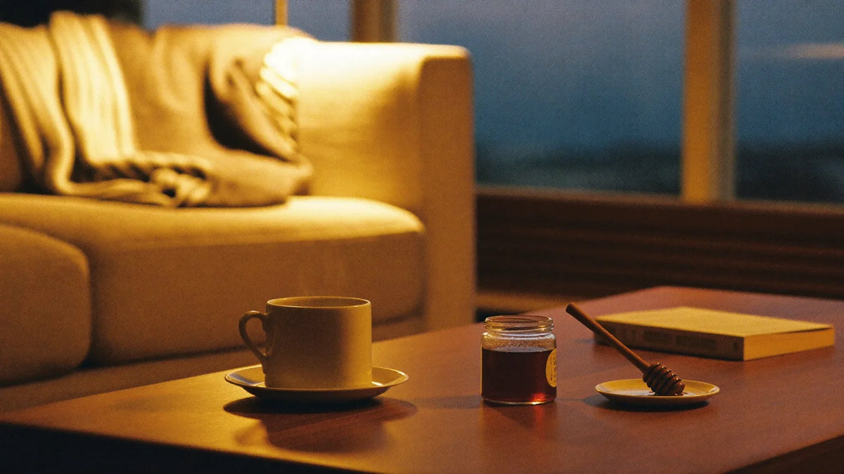 A quiet evening at home — warm lamplight, tea and a jar of honey. The mood mad honey is made for