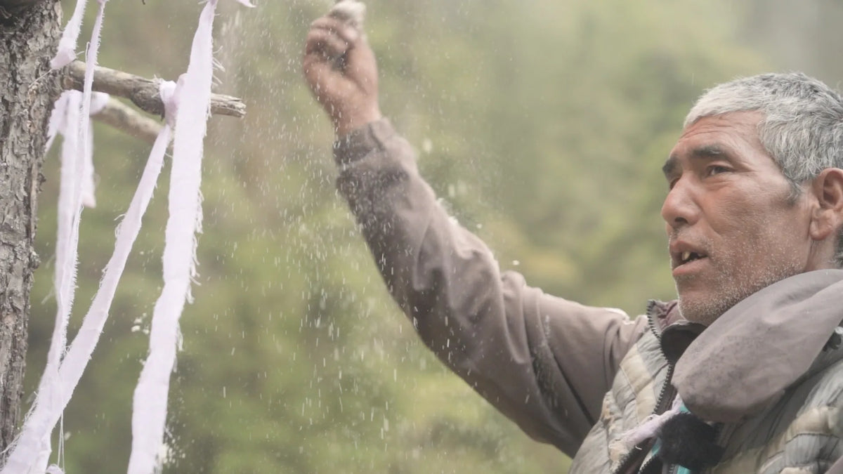 An elder honey hunter performing the traditional ceremony to thank the mountain before the climb