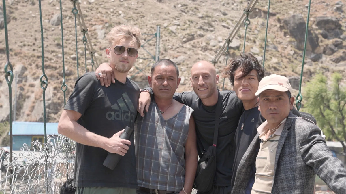 The Real Mad Honey founders arm-in-arm with their Nepali honey-hunting partners on a suspension bridge
