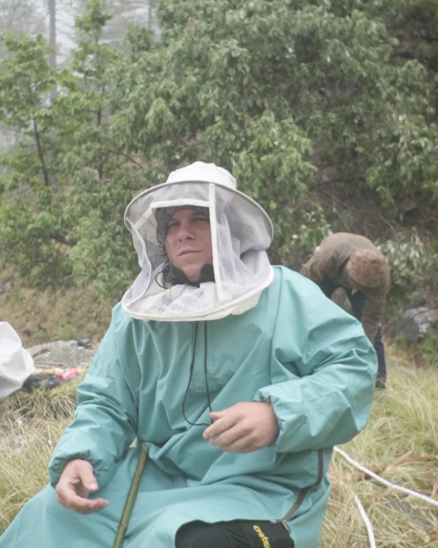 Our head of sourcing in a bee suit on a misty Himalayan cliffside, during the wild honey harvest
