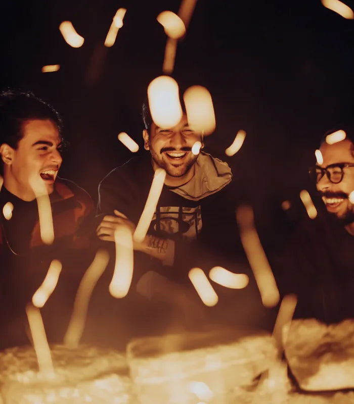 Friends laughing around a bonfire at night
