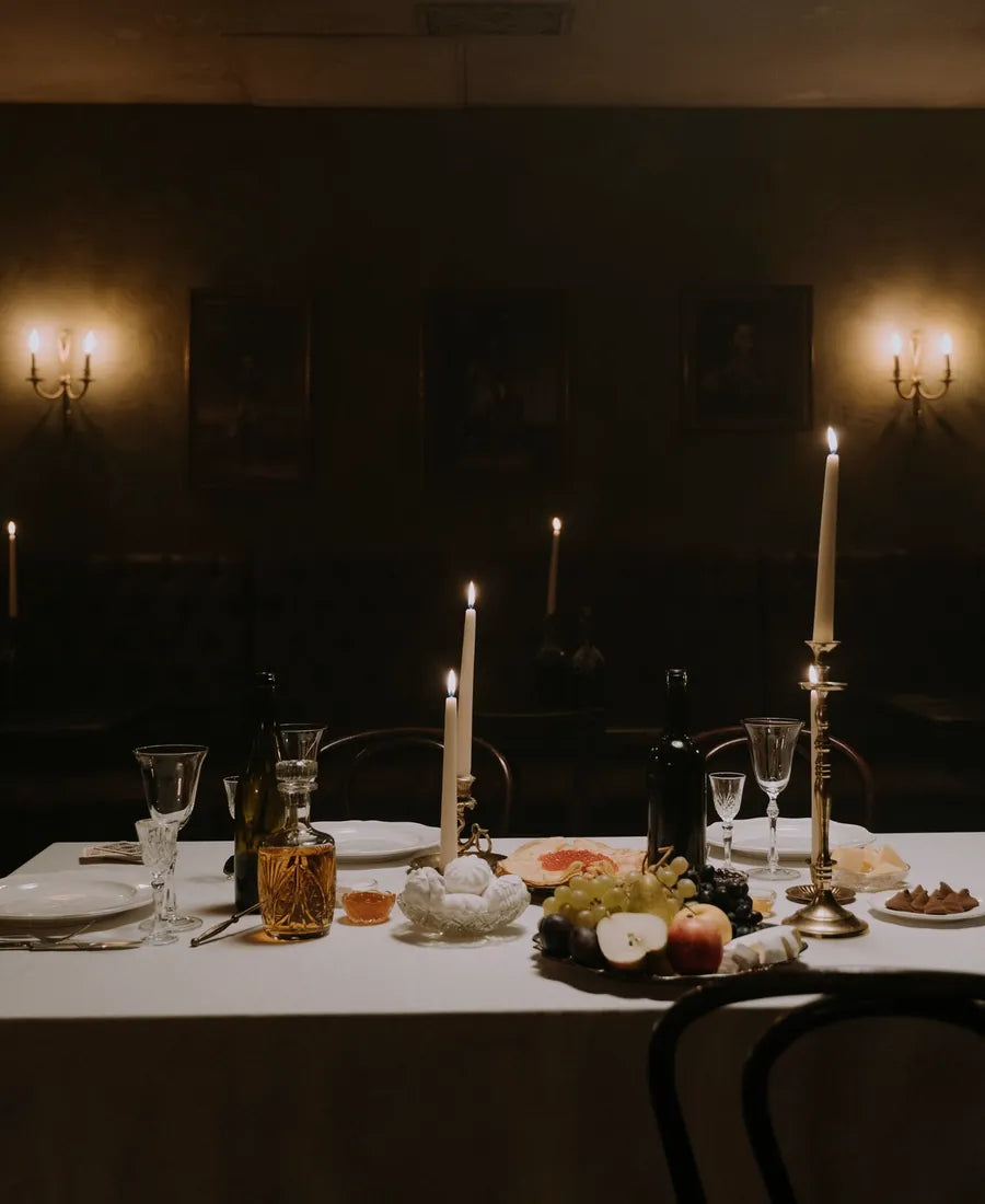 Candlelit table set for a shared evening in a dark gothic room